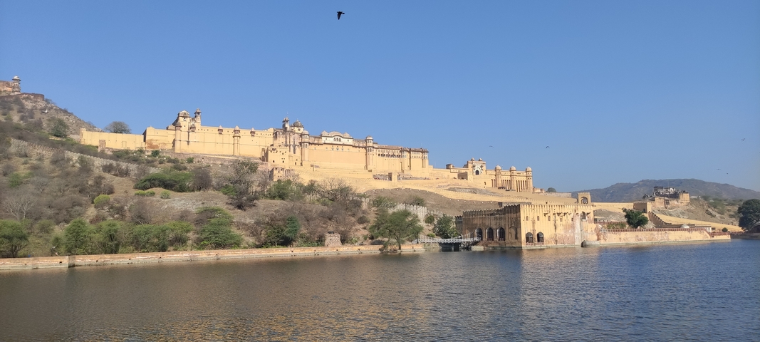 View of Amber Fort across the lake with hills in the background.