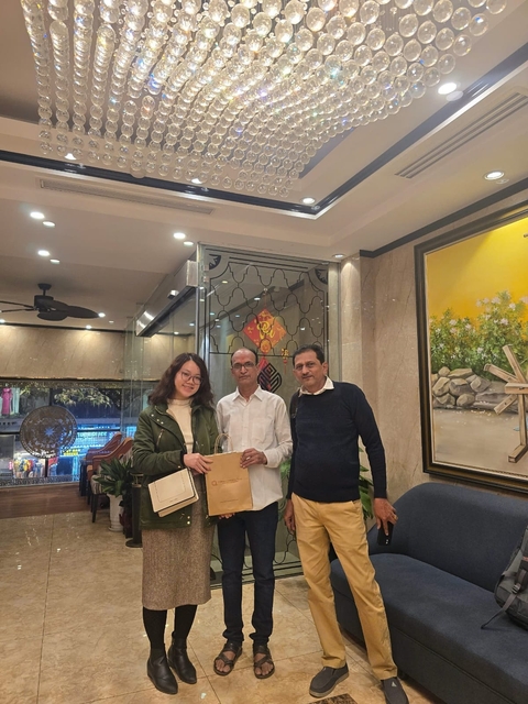 People posing indoors with a gift bag.