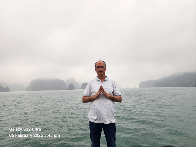 A man standing in front of misty waters with islands.