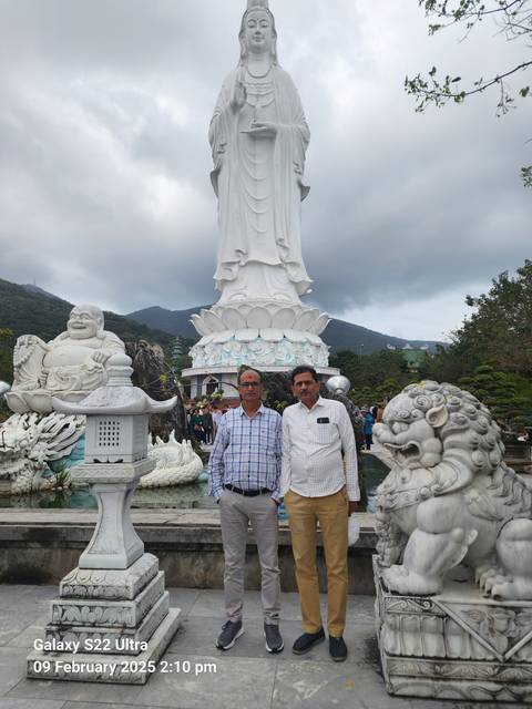 Two men standing in front of a large statue.