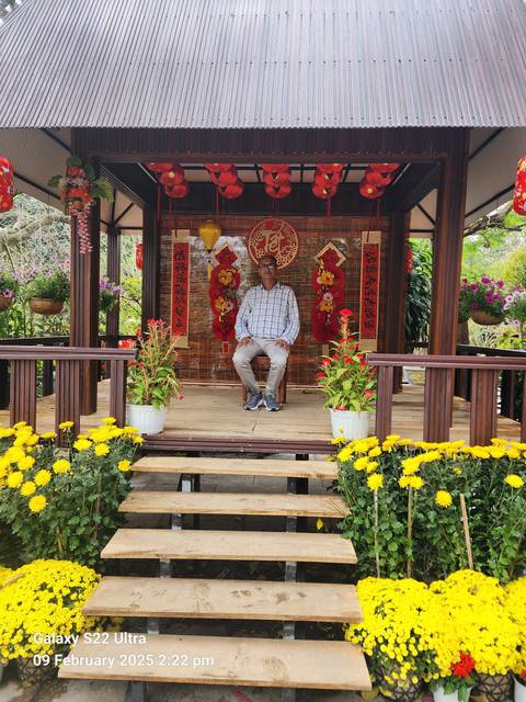 A man sitting in a decorated pavilion with flowers.