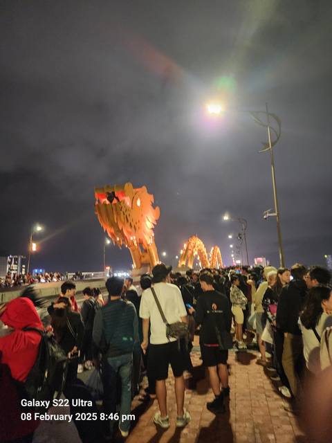 A busy night scene with a dragon bridge.