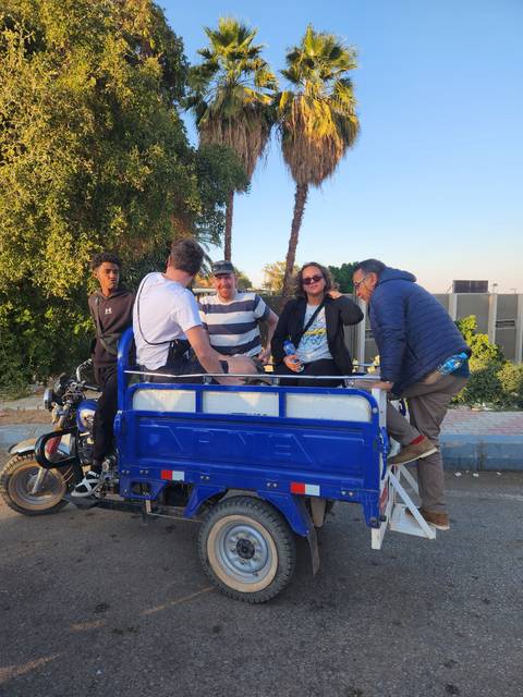 Group of people sitting on a cart or vehicle.