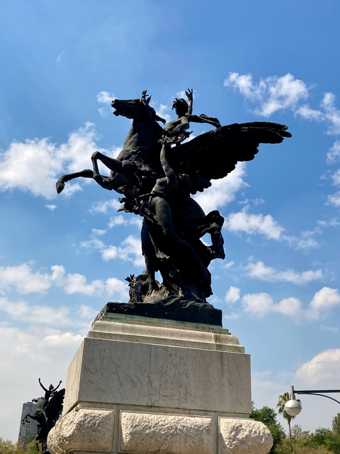       Silhouette of a Pegasus sculpture against a blue sky.
  