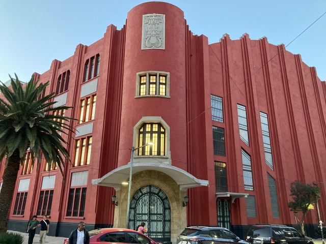 A red art deco building with illuminated windows.
