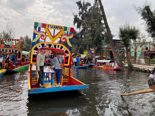       Colorful boats on a canal with people enjoying a day out.
  