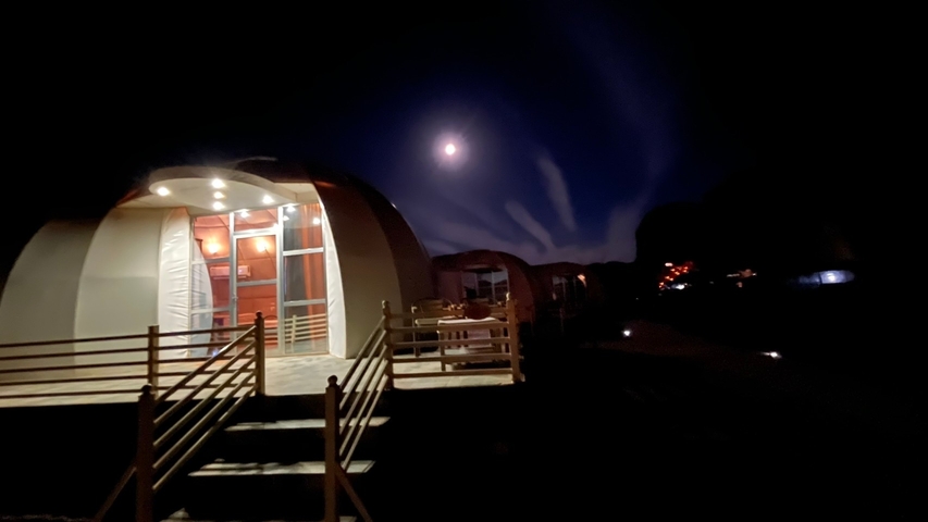 Night view of a dome structure with lights and moon.