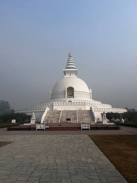 White stupa with steps and misty atmosphere.