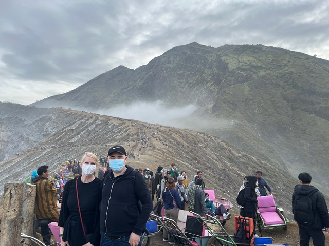 People wearing masks posing with a mountainous landscape in the background.