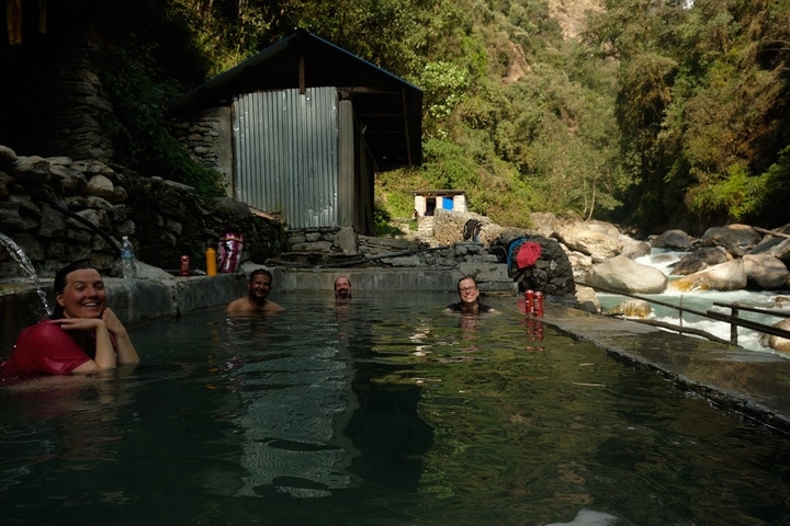       People relaxing in a natural hot spring by a river.
  