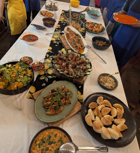 Variety of dishes on a buffet table including salads and grilled meat.
