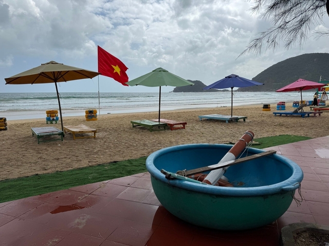       Beach scene with Vietnamese flag and colorful chairs.
  