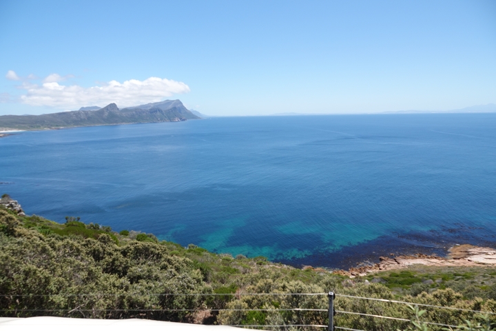 A stunning view of a coastline with a clear blue ocean and a distant mountain range.