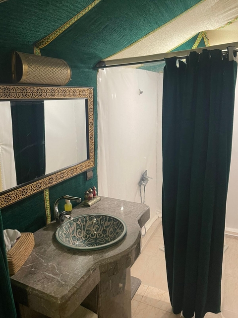       A bathroom with a decorated sink and a shower.
  