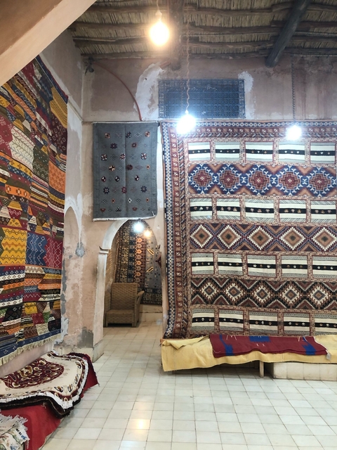      A market stall displaying a variety of traditional rugs.
  