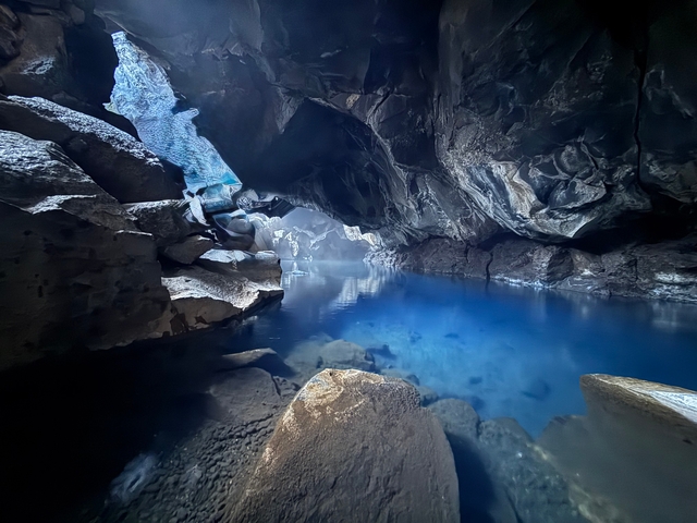 A serene hot spring inside a cave with crystal clear blue water.