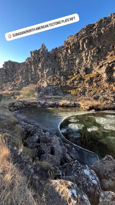       A small frozen pond surrounded by rocky terrain.
  