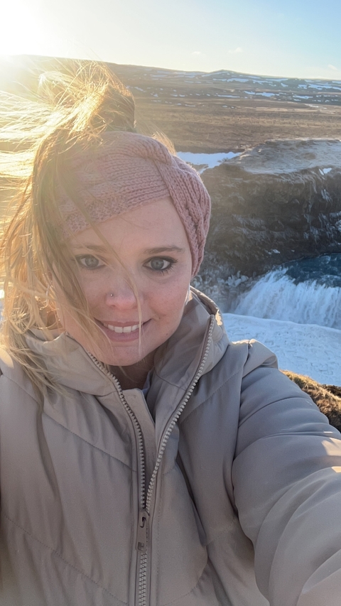       Woman smiling with a waterfall in the background.
  