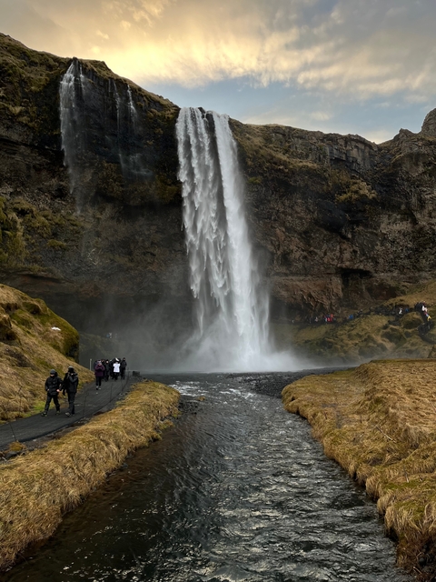       A large waterfall with visitors walking nearby.
  