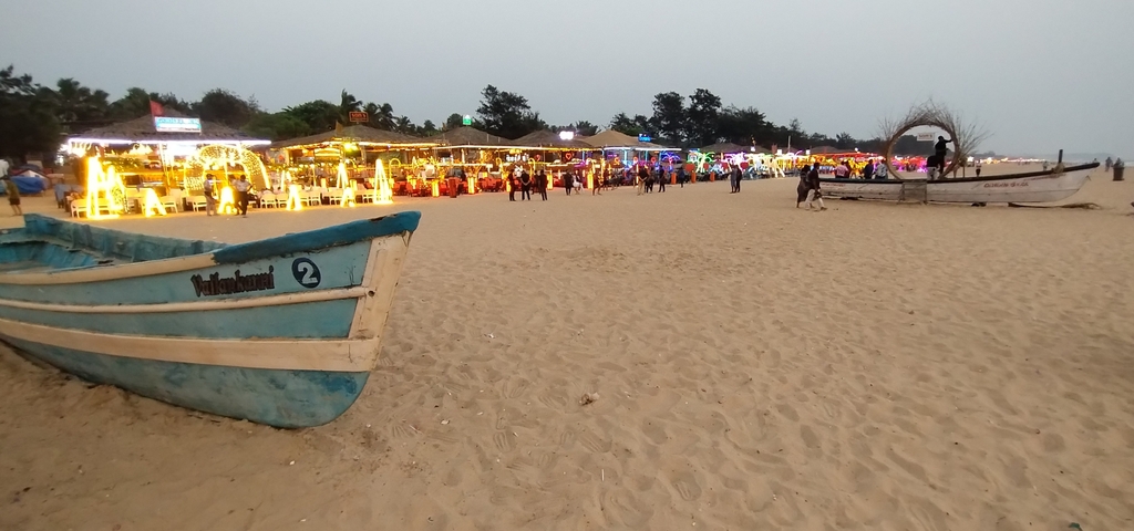 Beach market scene with lights and people in the evening.