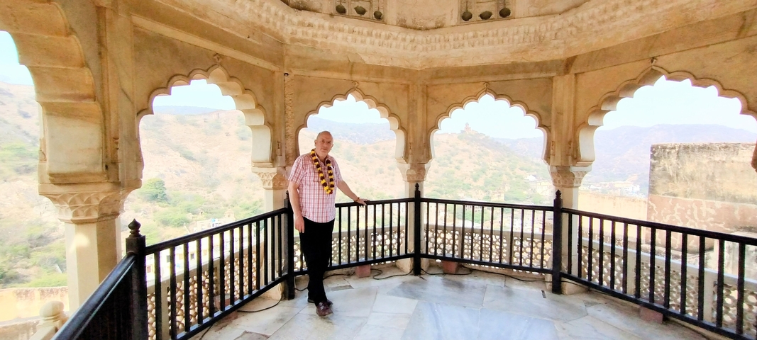 Person posing in an archway with scenic hills.