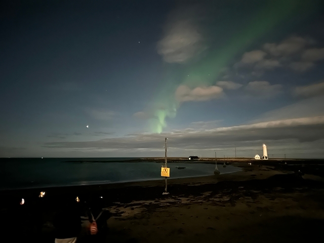       Northern lights over a coastal area at night.
  