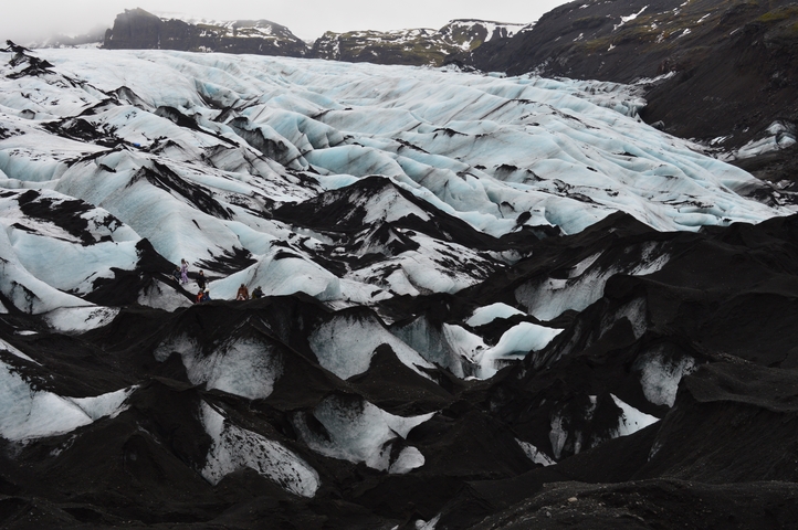       Group hiking on a glacier with dark and light contrast.
  