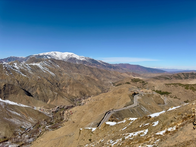 Mountain range with snow-capped peaks and winding road.