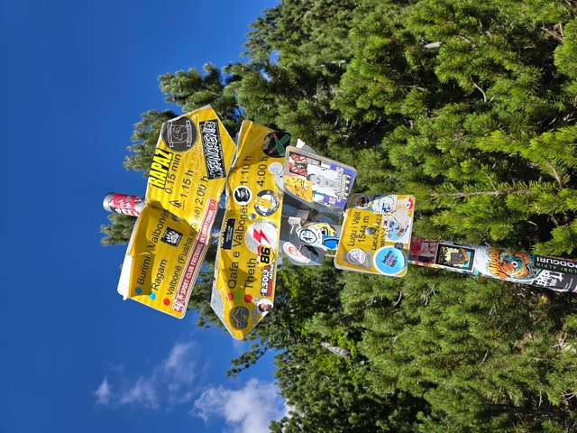Signs covered in stickers pointing to various hiking trails.