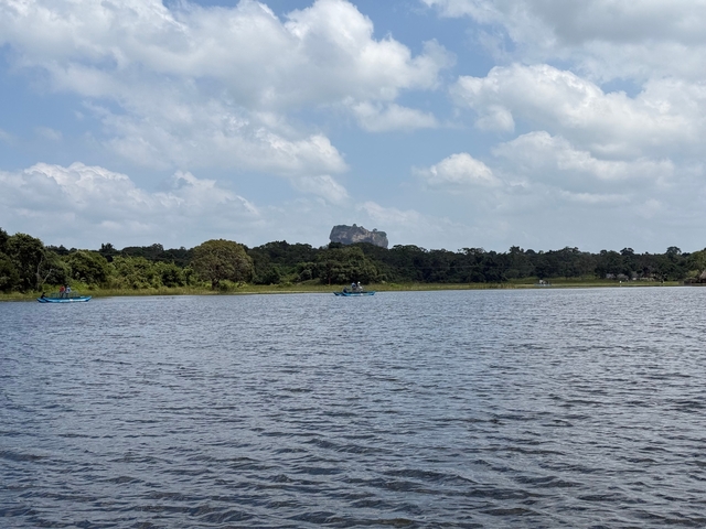 Scenic view of a lake with boats and a rock fortress in the distance.