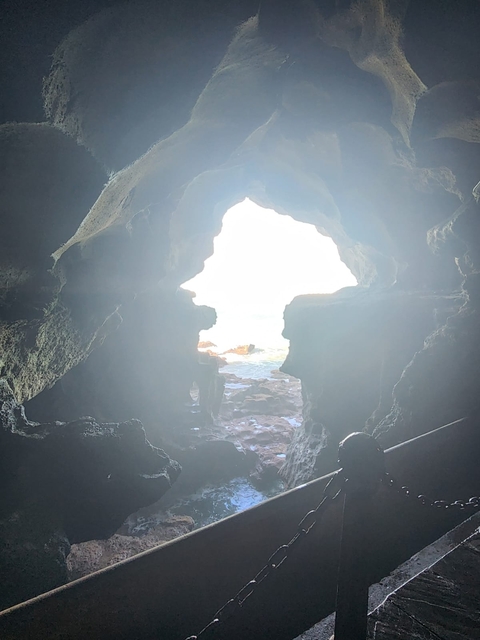 Interior view of a cave with a bright opening to the sea.