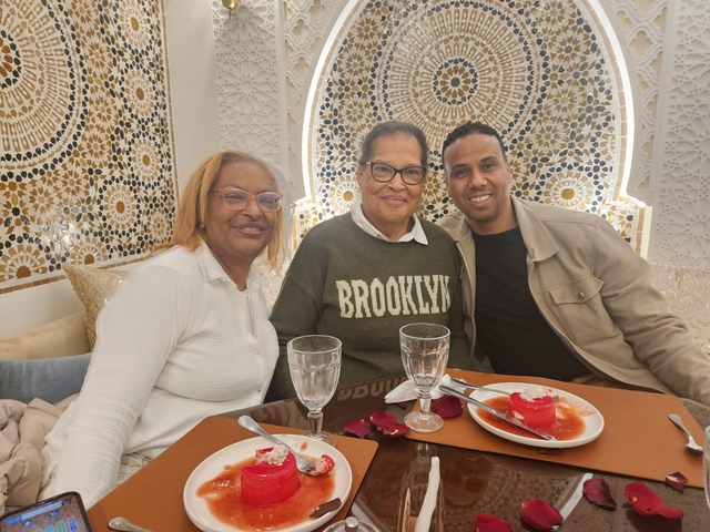 Restaurant setting with mosaic wall and three people smiling.