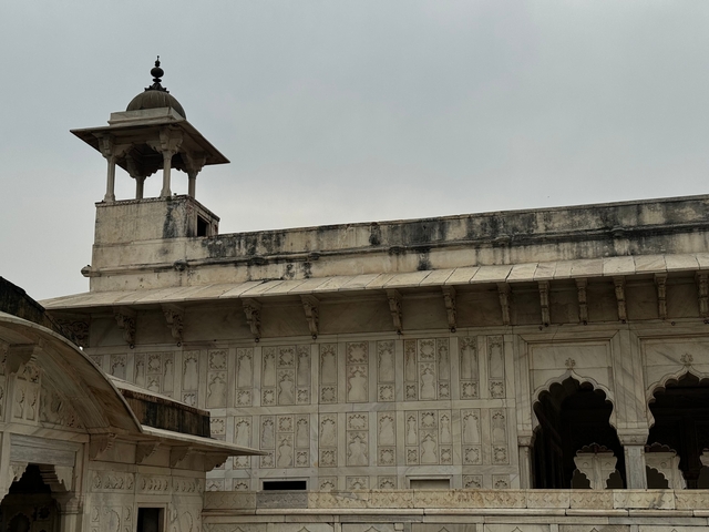 White marble building with intricate carvings and overcast sky.