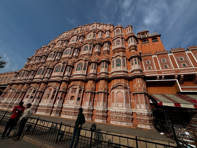 Hawa Mahal with its intricate facade and people walking past.