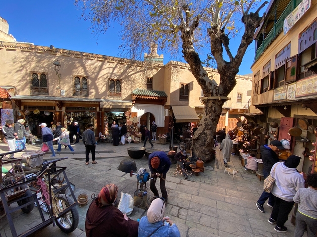 People in a vibrant Moroccan market with various goods displayed.