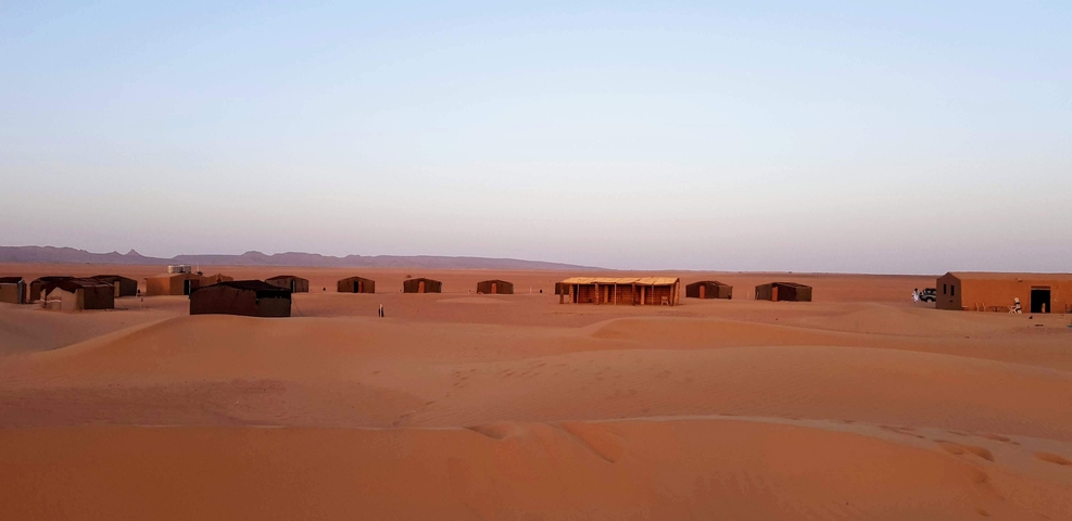 A desert campsite with tents visible in a sandy and remote area.