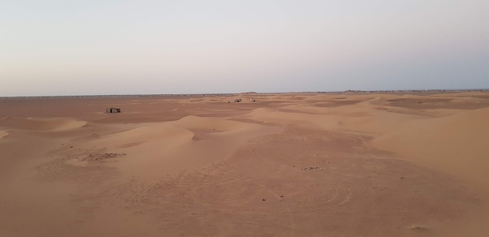 A vast desert landscape with sand dunes stretching into the distance.