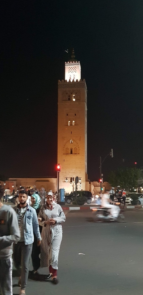       A night view of a tall, illuminated tower structure with lights around it.
  