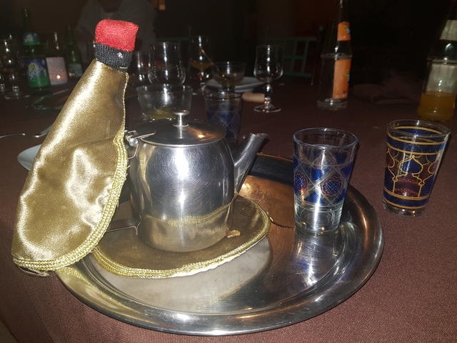 A traditional Moroccan tea set with a silver teapot and decorated glasses.
