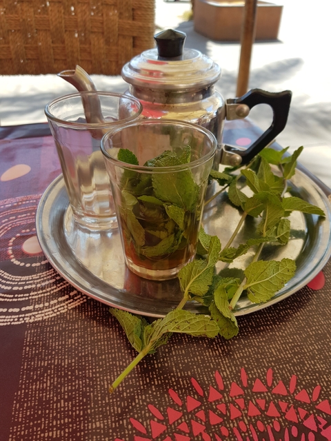       A glass of mint tea on a tray with fresh mint leaves.
  