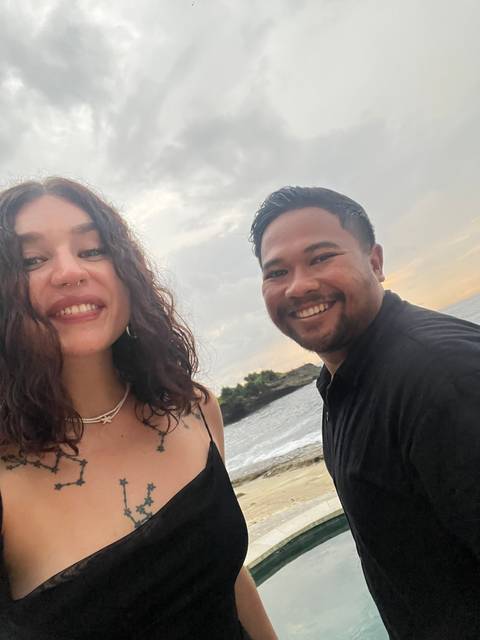 Two people smiling with a beach background.