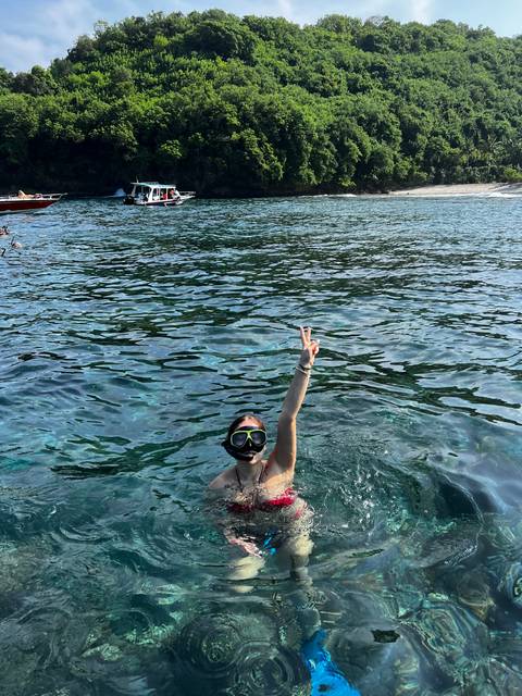 Person swimming with snorkel gear in clear water.