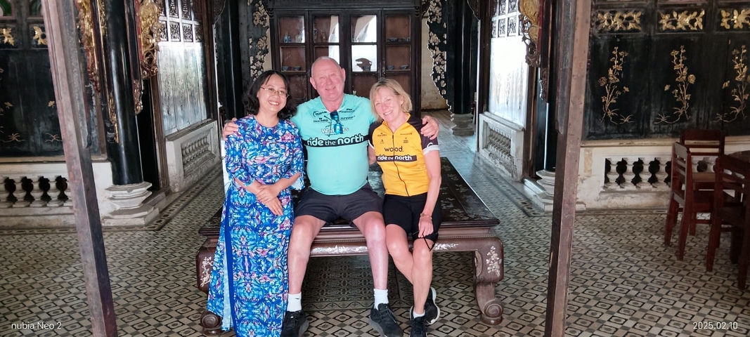 Three people sitting and posing inside a decorative building.