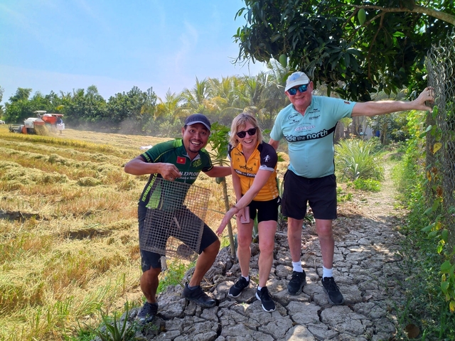 Three people standing in a field, holding a metal grid.