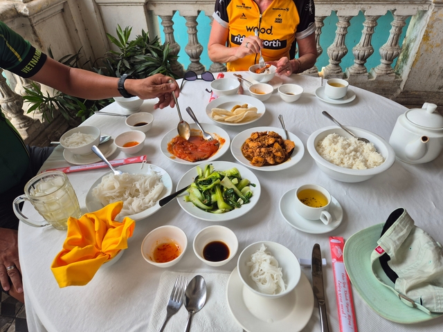 Table set with a variety of dishes, people serving food.