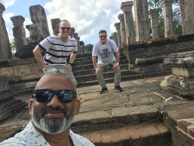 Three men posing on ancient ruins.
