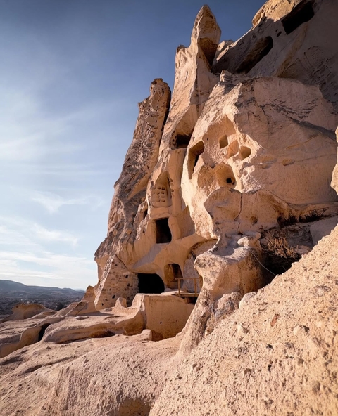 Rock-cut dwellings on a sunlit rock face.