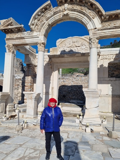       Person posing in front of ancient ruins with marble columns.
  