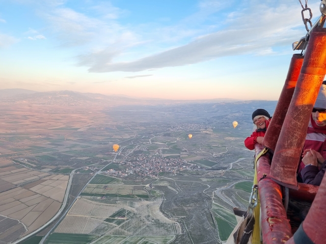       Hot air balloon ride over a vast landscape with other balloons in the distance.
  