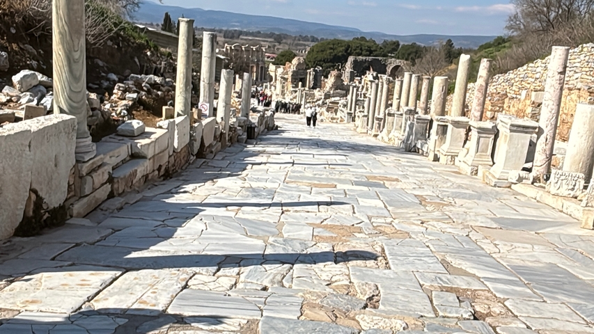       Marble street with ruins of columns and a distant landscape.
  